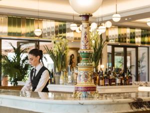 a woman standing behind a counter in a bar at Grecotel Filoxenia Kalamata in Kalamata