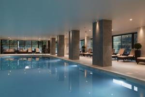 a swimming pool in a hotel with tables and chairs at St. Pierre Park Hotel & Golf in St. Peter Port