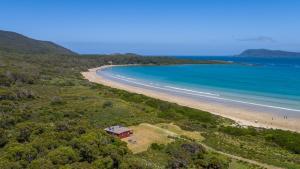 a house on a hill next to a beach at Cloudy Bay Cabin in South Bruny