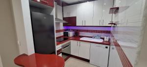 a kitchen with white cabinets and a red chair in it at Egabro Apartamento in Cabra +12 photos