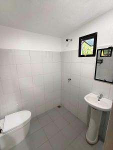a white bathroom with a toilet and a sink at travis homestay in Siquijor