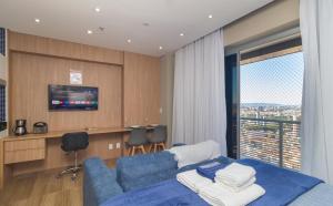 a living room with a blue couch and a tv at The CityPlex | Apartamentos Prime no Centro de Osasco in Osasco