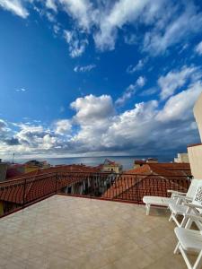 a balcony with chairs and a view of a city at LaDependance Hotel Scilla in Scilla