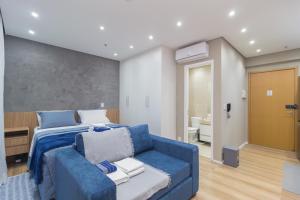 a bedroom with a blue bed and a couch at The CityPlex | Apartamentos Prime no Centro de Osasco in Osasco