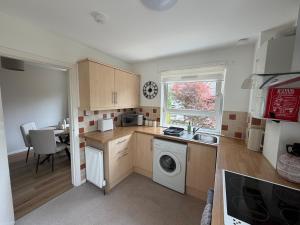 a kitchen with a sink and a washing machine at The Narrows - Macaulay Letting in Rhu