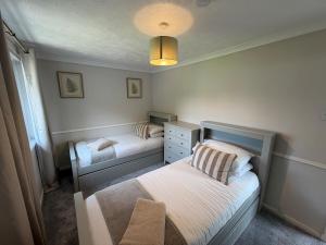 a small bedroom with two beds and a lamp at The Narrows - Macaulay Letting in Rhu