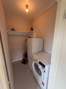 a small laundry room with a washer and dryer at The Narrows - Macaulay Letting in Rhu +5 photos