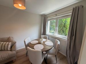 a dining room with a table and chairs and a window at The Narrows - Macaulay Letting in Rhu