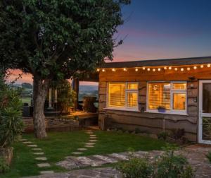 a house with a tree and lights on it at Cosy rustic cabin with hot tub and country views in Llanelli