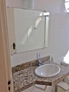 a bathroom with a sink and a mirror at Guarujá Apartment in Guarujá