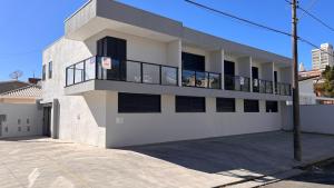 a white building with a balcony on top of it at Studio Chico 02 in Espirito Santo Do Pinhal