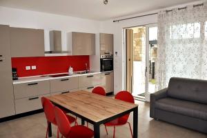 a kitchen with a wooden table and red chairs at Villetta Pima in Garda
