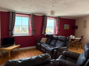 a living room with a leather couch and a table at Avondale Apartment Lahinch in Lahinch
