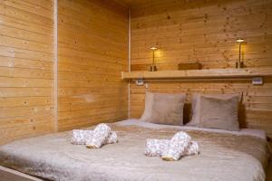 a bed with four pillows on it in a wooden room at Mama Chata a Mama Spa Beskydy in Bílá