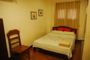 a small bedroom with a bed and a chair at Centro Mactan Suites in Mactan