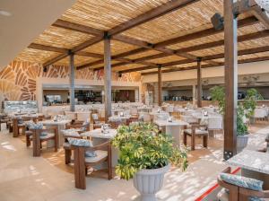 an empty restaurant with tables and chairs and plants at Adalya Art Side - Ultra All Inclusive in Side