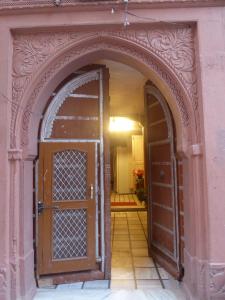 an archway in a pink building with an open door at Tanisha Heritage Haweli in Bikaner