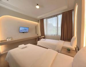 a hotel room with two beds and a flat screen tv at Tamashii Boutique Hotel in Bandung