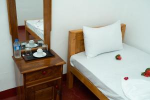 a room with a bed and a table with a mirror at Nilaveli Beach Bungalow in Trincomalee