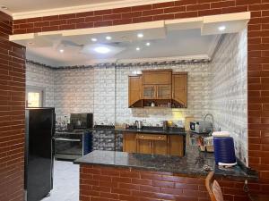 a kitchen with wooden cabinets and a brick wall at King mariout villa LA FIESTA in Borg El Arab