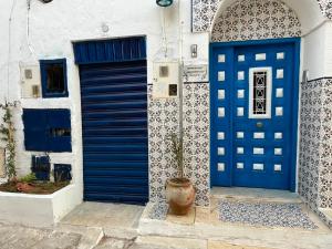 a house with blue doors and a potted plant at Dar zgolli in Kelibia