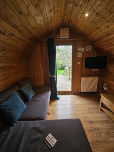 a room with a couch and a tv and a window at Mountain Edge Resort Mega pod 3 with Hot Tub in Church Stretton