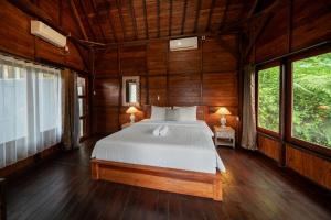 a bedroom with a bed in a wooden room with windows at Medukuh Point Hill in Karangasem
