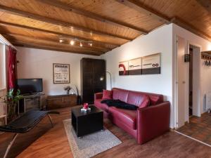 a living room with a red couch and a tv at Apartment Wohnung Wettstein by Interhome in Sörenberg