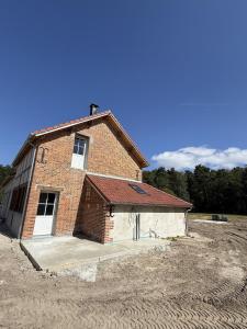 a brick building in a field next to a field at La Grange aux Etangs - Le Gîte in Sennely