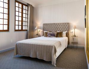 a bedroom with a large bed and two windows at Château de Fontager in Serves-sur-Rhône