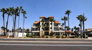 a large building with palm trees in front of a street at Huntington Beach Inn in Huntington Beach