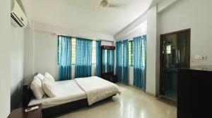 a bedroom with a bed and some windows at Neelima Resort in Cox's Bazar