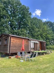 a cabin with chairs and a table and a red umbrella at Luční domek in Protivín