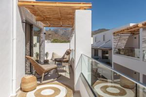 a balcony with chairs and a view of the mountains at South Coast Hotel in Makry Gialos