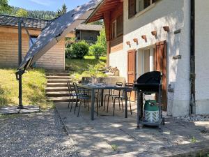 a patio with a table and chairs and a grill at Chalet Chalet Chaudoudoux - Les Paccots by Interhome in Les Paccots