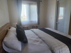 a bedroom with a large bed with pillows and a window at MD Amed Guest House in Amed
