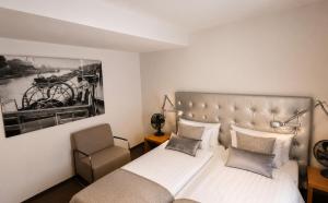 a bedroom with a bed and a chair at DORMERO Hotel Essen in Essen