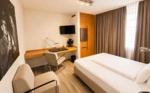 a hotel room with a bed and a desk at DORMERO Hotel Essen in Essen