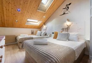 two beds in a room with wooden ceilings at Ski Lodge Sierra Nevada in Sierra Nevada