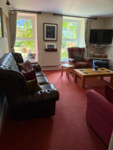 a living room with a leather couch and a coffee table at Ty Derw B & B in Dinas Mawddwy