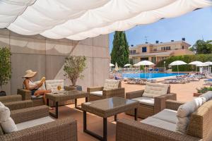 a woman sitting on a patio at a resort with a pool at Dorisol Buganvilia Studio Hotel in Funchal