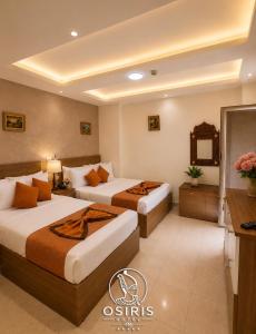 a hotel room with two beds and a television at Osiris Hotel Downtown in Cairo