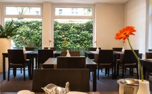a restaurant with tables and chairs and a large window at DORMERO Hotel Essen in Essen