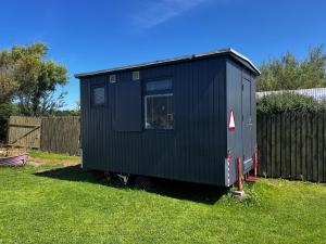 ein kleines schwarzes Haus, das im Gras steht in der Unterkunft The Crows Nest in Hirtshals + 13 Fotos