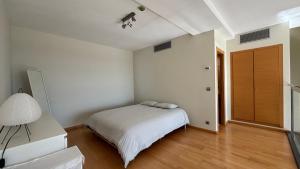 a white bedroom with a bed and a lamp at Loft en Valencia in Burjassot