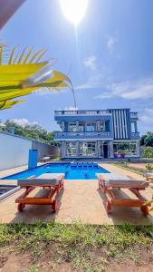 a swimming pool with two picnic tables in front of a building at J&T Holme Villa in Galu