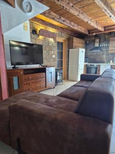 a living room with three brown couches and a tv at Kuća za odmor Silba in Silba