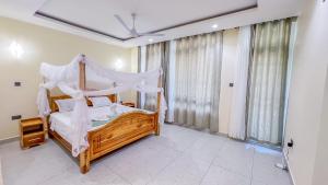 a bedroom with a wooden bed with a canopy at J&T Holme Villa in Galu +34 photos