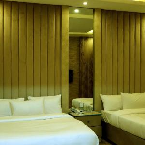 a hotel room with two beds and a mirror at Hotel City Top In Murree in Murree