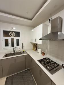 a white kitchen with a sink and a stove at Taqah Beach Front Apartment in Ţāqah +14 photos